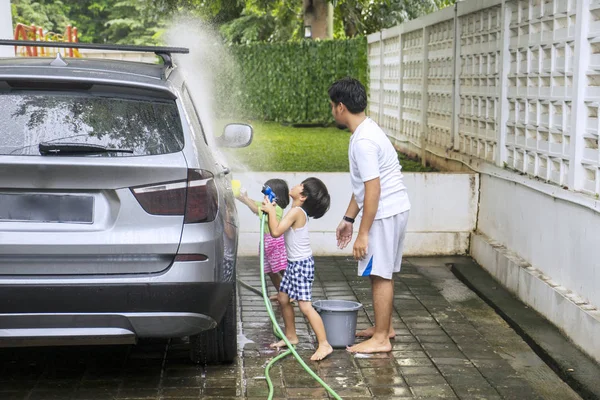 Duas crianças e seu pai lavar um carro em casa — Fotografia de Stock