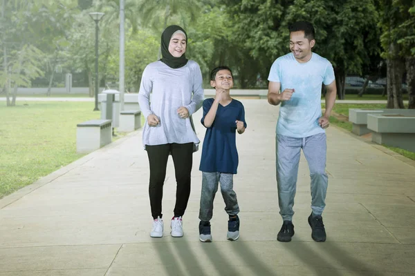 Счастливая мусульманская семья, бегущая вместе в парке — стоковое фото