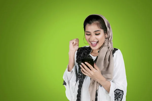 Muslim woman looks happy with phone on studio — Stock Photo, Image