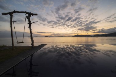 Gün doğumunda boş salıncak ile Egzotik deniz manzarası