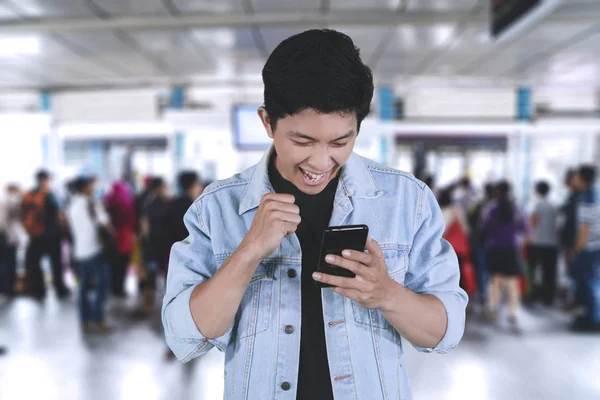 Happy man with smartphone in the bus shelter