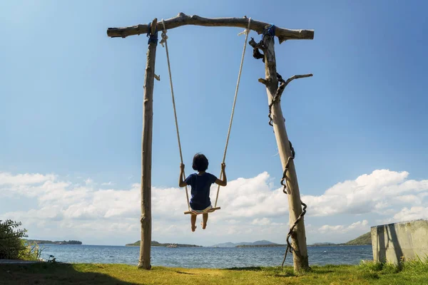 小さな女の子は、ブランコに海景を楽しんでいます — ストック写真