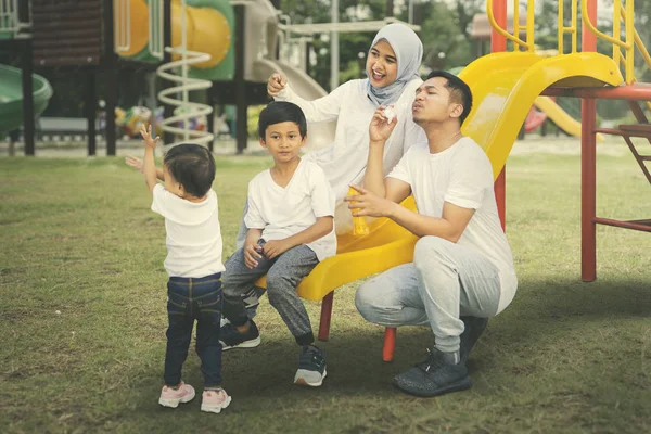 Família muçulmana brinca com bolhas no parque infantil — Fotografia de Stock