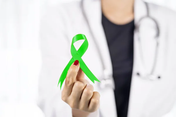 Female physician holds a lime green ribbon — Stock Photo, Image