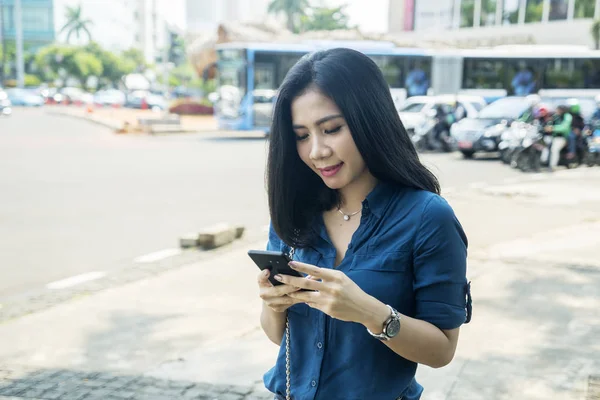 Menina bonita usando um telefone celular na beira da estrada — Fotografia de Stock