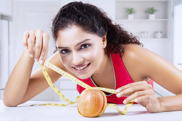 Smiling woman measuring fresh apple at home — Stock Photo, Image