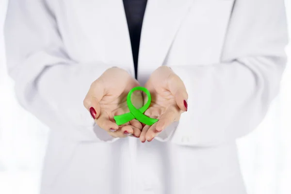 Unknown doctor hands hold a lime green ribbon — Stock Photo, Image