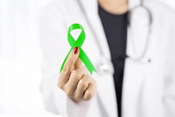 Young female doctor shows a lime green ribbon — Stock Photo, Image