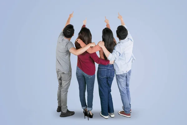 Cuatro jóvenes señalando algo juntos — Foto de Stock