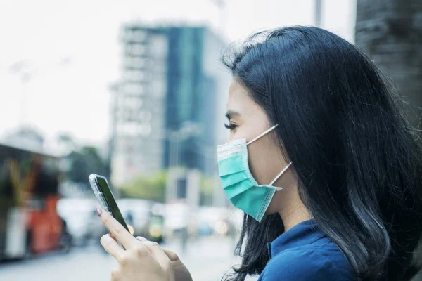 Vrouw met masker en smartphone buiten — Stockfoto