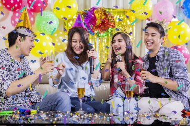 Gençler doğum günü partisinde birlikte şarkı söylüyorlar.