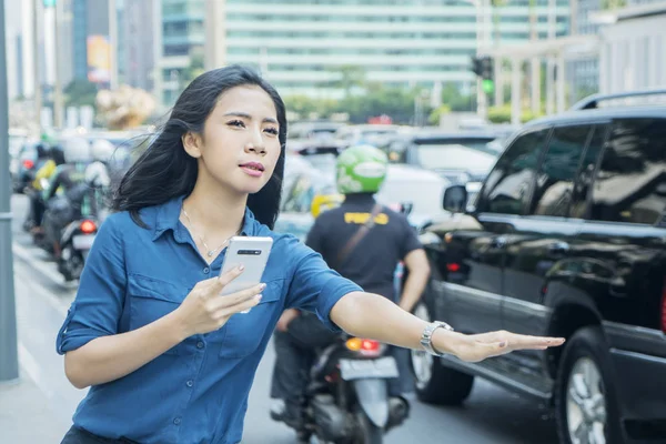 Mujer joven deteniendo taxi en línea — Foto de Stock