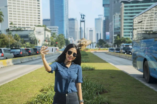 Ung kvinna tar foto med välkomststaty — Stockfoto