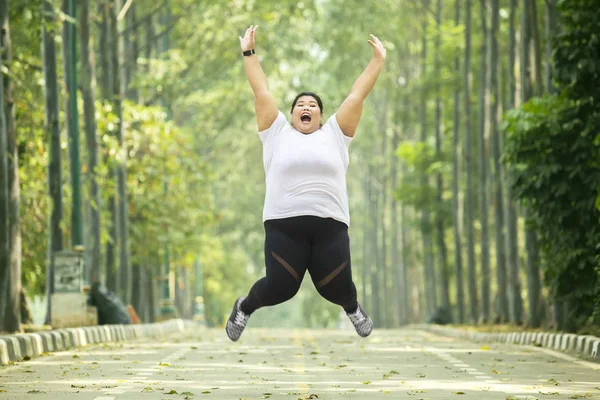 Upphetsad fet kvinna hoppar på vägen — Stockfoto