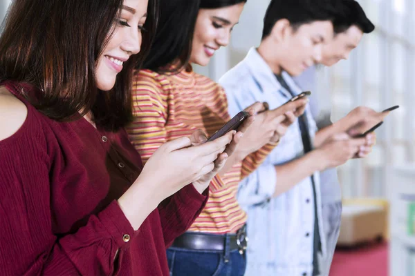 Vier Schüler surfen mit Smartphones im Internet — Stockfoto