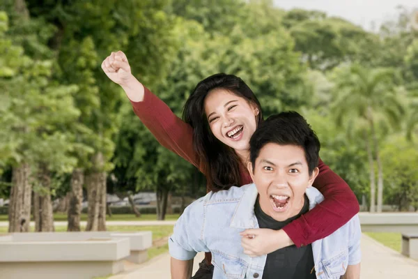 Glückliches Paar spielt Huckepack-Fahrt im Park — Stockfoto
