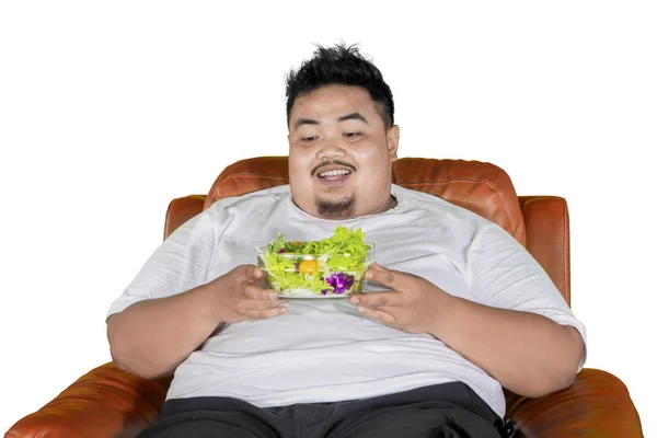 Homem gordo feliz mantém uma tigela de saladas no estúdio — Fotografia de Stock