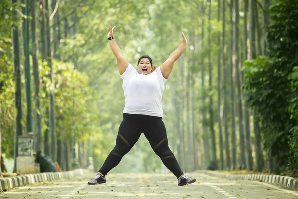 Happy obese woman jumps on the road — Stock Photo, Image