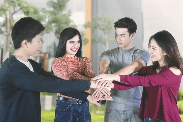 Happy young people joining hands in the park — Stock Photo, Image