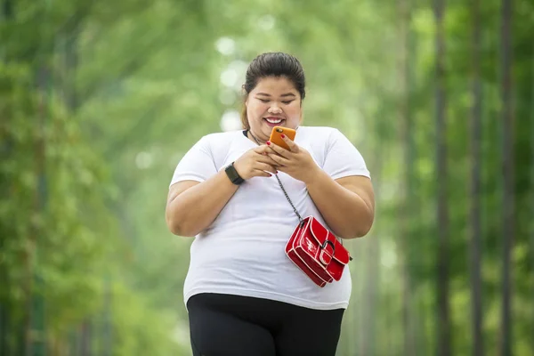 Mujer con sobrepeso usando un teléfono en el parque — Foto de Stock