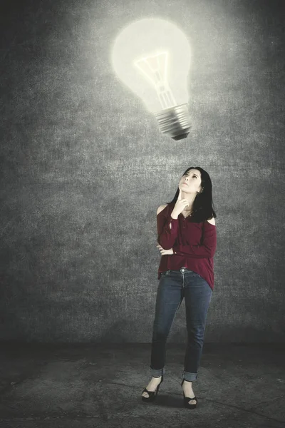 Young woman looking at a bright bulb — 스톡 사진