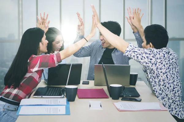Business team gives high five hands near the window