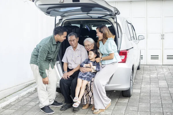 Linda niña sentada con su familia en el maletero del coche —  Fotos de Stock