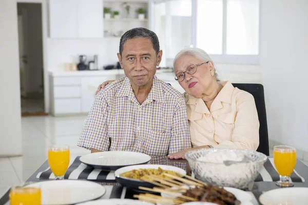 Coppia anziana seduta davanti al tavolo da pranzo — Foto Stock