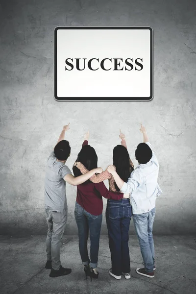 Four young people pointing at success word — Stock Photo, Image