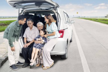 Araba bagajında oturan çok nesilli aile