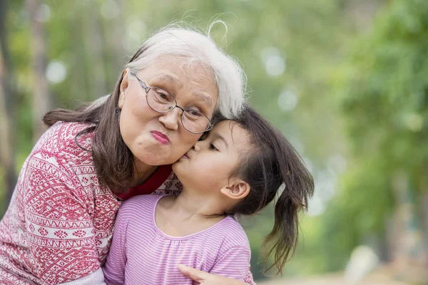 Glückliche ältere Frau von ihrer Enkelin geküsst — Stockfoto