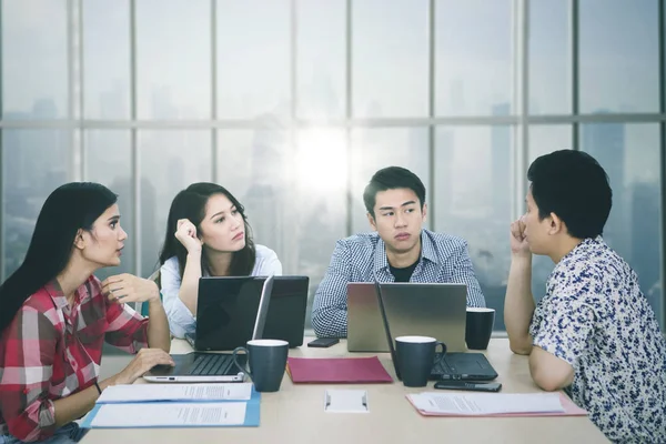 Mladý muž diskutuje se svými partnery v kanceláři — Stock fotografie