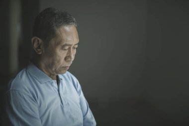 Yaşlı adam karanlık odada üzgün görünüyor