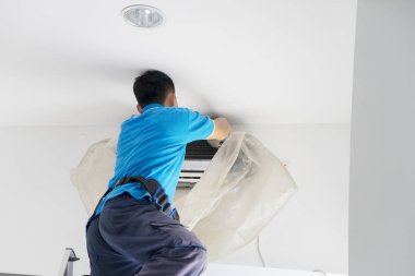 Bir klimayı tozdan temizleyen erkek işçi