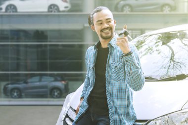 Genç adam yeni araba anahtarını dağıtıcıda büküyor.