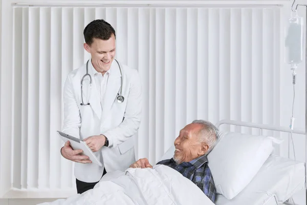 Amerikansk läkare visar tablett på äldre patient — Stockfoto