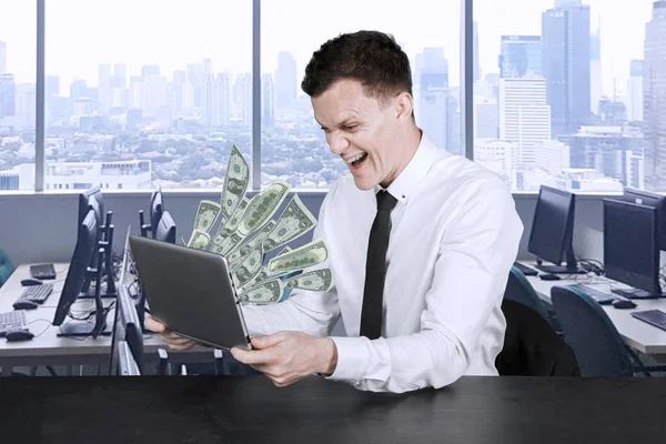 Businessman looks at money out of his laptop — Stock Photo, Image