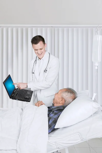 Caucásico médico muestra un ordenador portátil a su paciente —  Fotos de Stock
