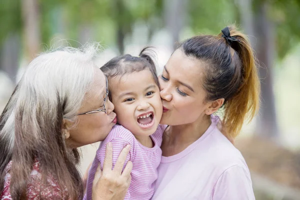 Bonito menina beijada por sua mãe e avó — Fotografia de Stock