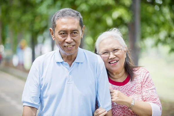 Elderly man embraced by his wife on the road — Stock Photo, Image