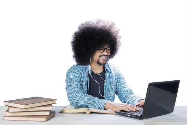 Frizzy student met behulp van een laptop en headset op Studio — Stockfoto