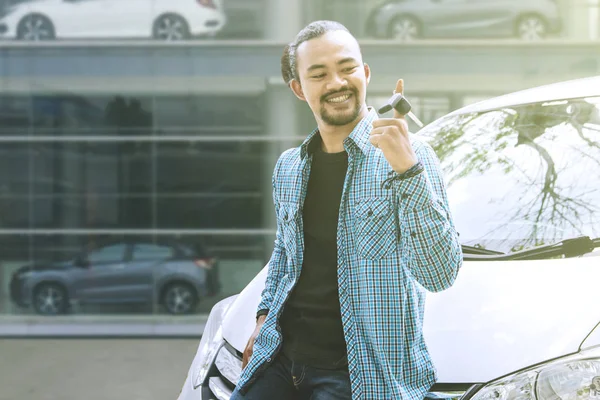 Genç adam yeni araba anahtarını dağıtıcıda büküyor.