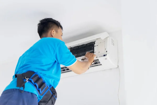 Mladý technik čistí klimatizaci s látkou — Stock fotografie