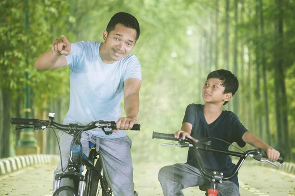 Asiatischer Mann radelt mit seinem Sohn im Park — Stockfoto