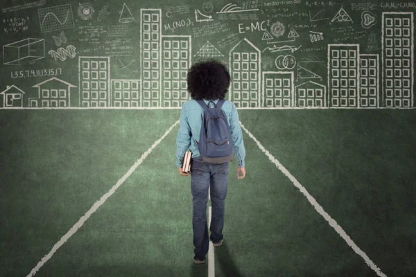 Afro estudiante universitario caminando sobre una pizarra — Foto de Stock