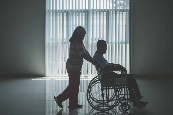 Ηλικιωμένη γυναίκα πιέζει τον άντρα της σε αναπηρικό καροτσάκι — Φωτογραφία Αρχείου