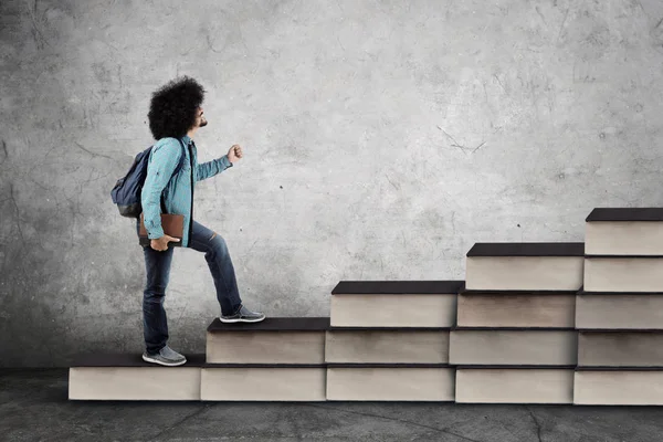 Afro estudante universitário masculino caminha na escada dos livros — Fotografia de Stock