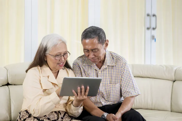 Cuplu în vârstă folosind un laptop pe canapea — Fotografie, imagine de stoc