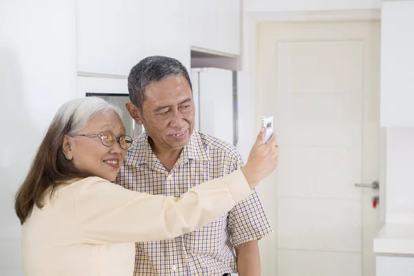 Anziani coppia prendendo un selfie insieme a casa — Foto Stock