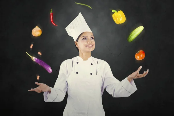 Femme chef jongle ingrédients alimentaires dans la chambre noire — Photo